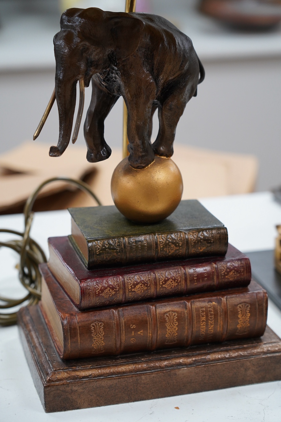 A Thomas Blakemore style ‘elephant’ and faux book table lamp with shade, 64cm. Condition - good, not tested as working